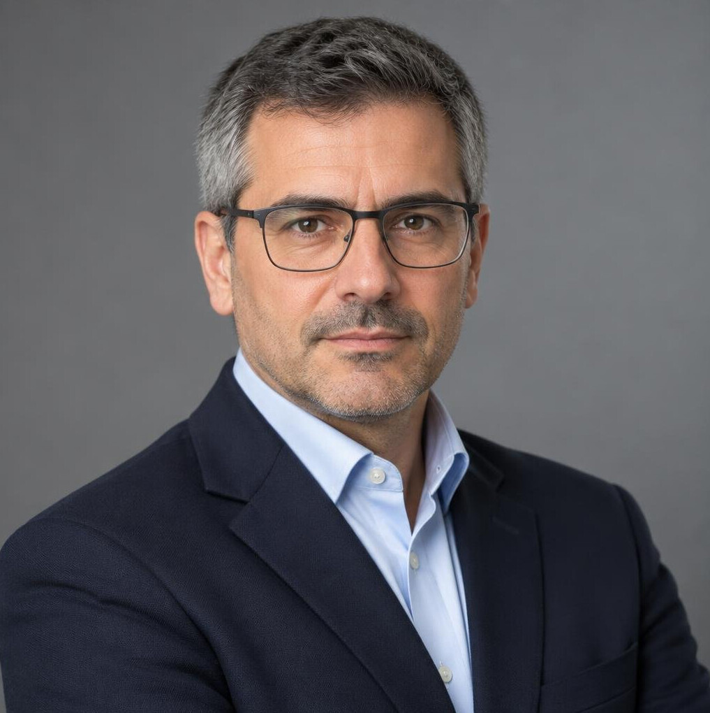 Studio portrait of a Portuguese man in his forties wearing glasses and a blazer